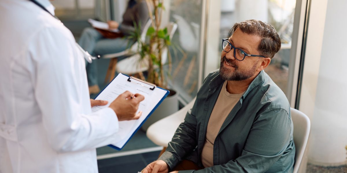 Happy mature man communicating with a doctor in waiting room at the clinic.