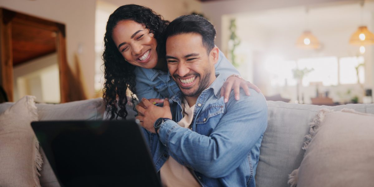 Home, couple and hug with laptop for laughing, streaming online and check movie for bonding together. Sofa, woman and man with technology for entertainment website, platform and happiness with love